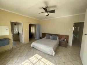 a bedroom with a bed and a ceiling fan at Vaaldam @ Sgt Pepper’s Holiday Home in Oranjeville