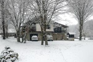 a snow covered house with cars parked in front of it at Vikendica Verići- Banja Luka in Jankovići