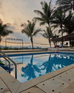 a swimming pool with palm trees in the background at Off The Grid Glamps in Khopoli