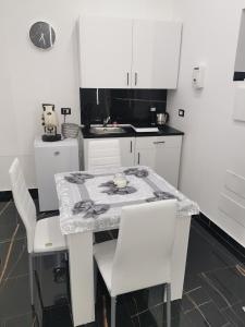 a kitchen with a table and white chairs at La casetta di gra in Palermo