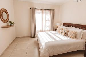 a bedroom with a large white bed with a window at Chawal @ Swartwithpens in Marloth Park