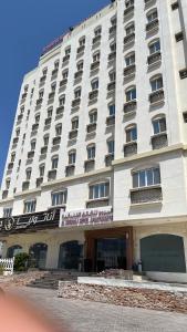 a large white building with a sign on it at Al Murooj Hotel Apartments in Muscat