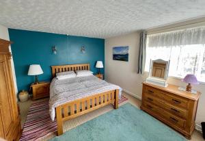 - une chambre avec un grand lit et un mur bleu dans l'établissement Tornaroan Cottage, à Ballycastle