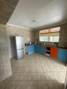 a large kitchen with blue cabinets and a refrigerator at Vaaldam @ Sgt Pepper’s Holiday Home in Oranjeville