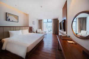 een hotelkamer met een groot bed en een spiegel bij Green Beach Nha Trang in Nha Trang