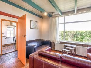 een woonkamer met lederen meubels en een groot raam bij Quaint Holiday Home in Nieuwvliet Bad near Seabeach in Nieuwvliet-Bad
