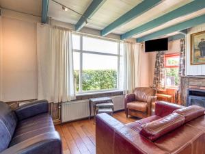 een woonkamer met een leren bank en een televisie bij Quaint Holiday Home in Nieuwvliet Bad near Seabeach in Nieuwvliet-Bad