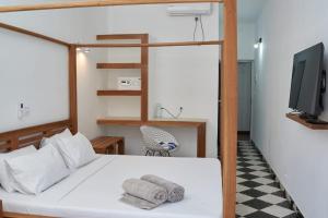 a bedroom with a bed with a television and towels at JIRAJIRA HOTEL in Nosy Be