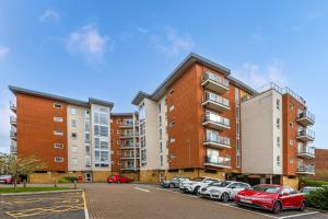 a parking lot with cars parked in front of a building at Business & Family Friendly Accommodation with FREE Private Gated Parking in Hatfield - Business Park, Hertfordshire University, Fast trains to London in Hatfield