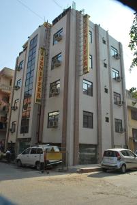 un gran edificio con coches estacionados frente a él en Hotel Jeniffer Inn en Nueva Delhi