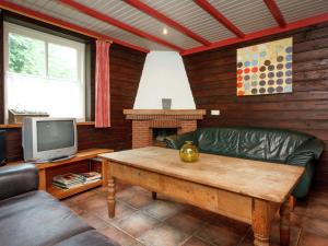 een woonkamer met een bank en een tv bij Cozy group house in Reusel in a natural environment in Lage Mierde