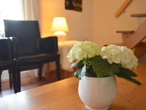 un jarrón blanco con flores blancas en una mesa en Holiday Home in Geesteren with Roof Terrace Garden Furniture, en Geesteren