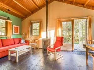 sala de estar con sofá rojo y sillas en Tranquil Holiday Home in Lage Zwaluwe with Terrace, en Lage Zwaluwe