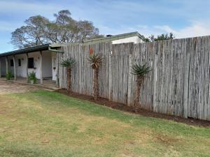 a fence with two palm trees in front of a house at The Ranch House at African Safari Lodge in Grahamstown
