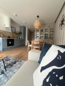 a living room with a white couch and a kitchen at Blue Apartament - HOME APART in Ostróda