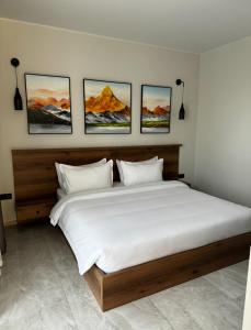 a bedroom with a large bed with four paintings on the wall at Hotel 28 in Bishkek
