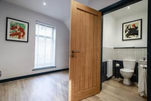 a bathroom with a toilet and a wooden door at May Disc - Long Stay - Contractors in Bristol