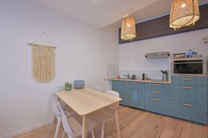 una cucina con tavolo in legno e armadi blu di Studio Andréa - Proche Théatres et Place des corps saints - WIFI ad Avignone Altre 20 foto