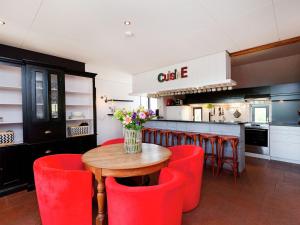 a kitchen with a wooden table and red chairs at Atmospheric country house in Asten on a golf course in Asten