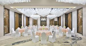 un salón de banquetes con mesas y sillas blancas y lámparas de araña en Sheraton Colombo Hotel, en Colombo