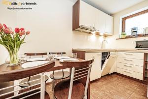 a kitchen with a table with chairs and a vase of flowers at Baltic Apartments - Hotelik Przy Promenadzie in Świnoujście