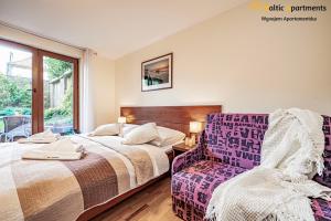 1 dormitorio con 2 camas y 1 silla en Baltic Apartments - Hotelik Przy Promenadzie, en Świnoujście