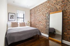 a bedroom with a brick wall and a bed with a mirror at West Village 1br w wd nr bars restaurants NYC-1133 in New York