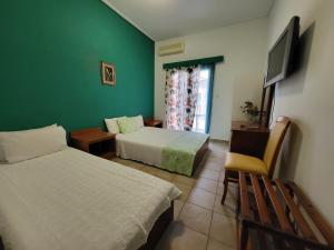 een hotelkamer met 2 bedden en een televisie bij PANTHEON HOLIDAY INN in Kamena Vourla