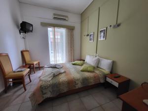 a bedroom with a bed and two chairs and a window at PANTHEON HOLIDAY INN in Kamena Vourla