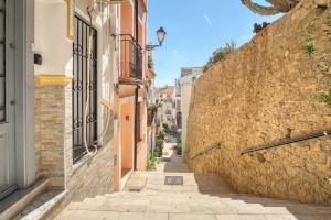 een steegje met gebouwen en een stenen muur bij Cueva Alicante in Alicante