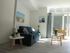 sala de estar con sofá azul y mesas en Stunning apartment in Schoorl North Holland you can bike to the beach, en Schoorl