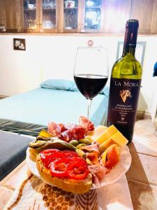 un piatto di cibo, una bottiglia di vino e un bicchiere di Monolocale Rustico Mamma Piera a Manciano