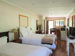 um quarto de hotel com duas camas e uma televisão em The Sleeping Bao B&B em Pietermaritzburg