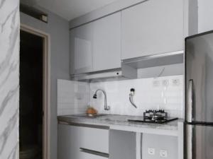 a white kitchen with a sink and a refrigerator at RedLiving Apartemen Bogor Valley - Paulina Property Tower A in Kalibata 1 +18 photos
