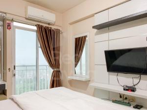 a bedroom with a bed and a tv and a window at RedLiving Apartemen Bogor Valley - Paulina Property Tower A in Kalibata 1