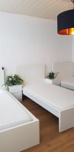 a white room with two white beds and two plants at Apartment Hannover-Hemmingen in Hemmingen