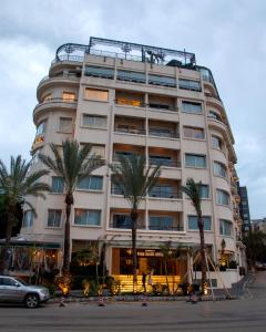 a large white building with palm trees in front of it at Warwick Palm Beach Hotel in Beirut