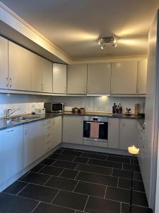 a kitchen with white cabinets and a black tile floor at Sjarmerende Bjelbølstølen in Beitostøl