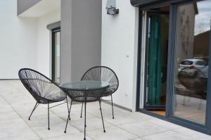 2 sillas y una mesa de cristal en el patio en Business Living Oberkochen, en Oberkochen