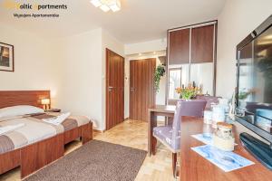 a hotel room with a bed and a desk and a television at Baltic Apartments - Hotelik Przy Promenadzie in Świnoujście
