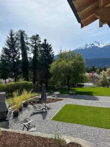 a garden with a table and an umbrella and mountains at Wohnung mit Garten und Panoramablick in Innsbruck in Innsbruck