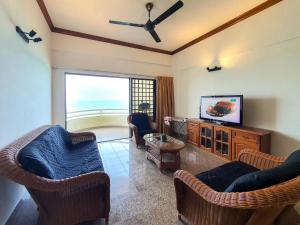 uma sala de estar com cadeiras e uma televisão de ecrã plano em 'Sunny seaview condo' at Regency by Shine Stay em Porto Dickson