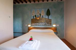 スカンサーノにあるSasseta Altaの白いベッドと壁に絵画が飾られたベッドルーム1室