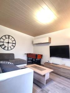 ein Wohnzimmer mit einem Sofa, einem TV und einem Tisch in der Unterkunft MAISON COSY 7 minutes des frontières in Rosenau