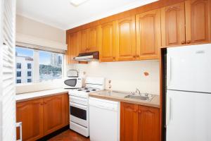 eine Küche mit Holzschränken und einem weißen Kühlschrank in der Unterkunft Harbourside Apartment with Spectacular Pool in Sydney