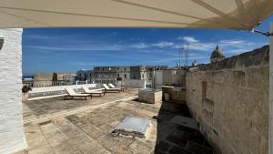 Cette chambre offre une vue sur le toit doté de chaises et de tables. dans l'établissement Residenza Garibaldi, à Monopoli