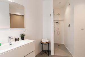 La salle de bains blanche est pourvue d'un lavabo et d'une douche. dans l'établissement Amare Suite & Apartments, à Bellaria-Igea Marina