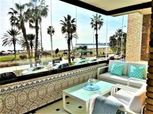 a balcony with a view of the beach and palm trees at Frente a la playa Malagueta-Ciudad Melilla, 6 personas in Málaga