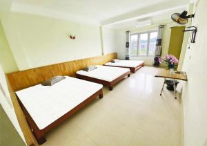 uma fila de camas num quarto com flores em Coto Plus Hotel & Restaurant em Quang Ninh