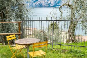 drewniany stół i dwa krzesła siedzące obok płotu w obiekcie Ca de l'Angelon -- Vittoria house w Brenzone sul Garda